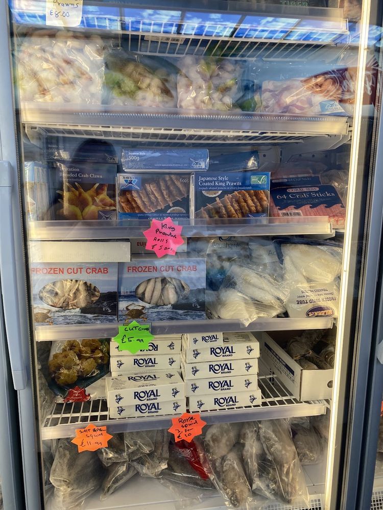 A stocked open freezer cabinet full of bagged frozen seafood