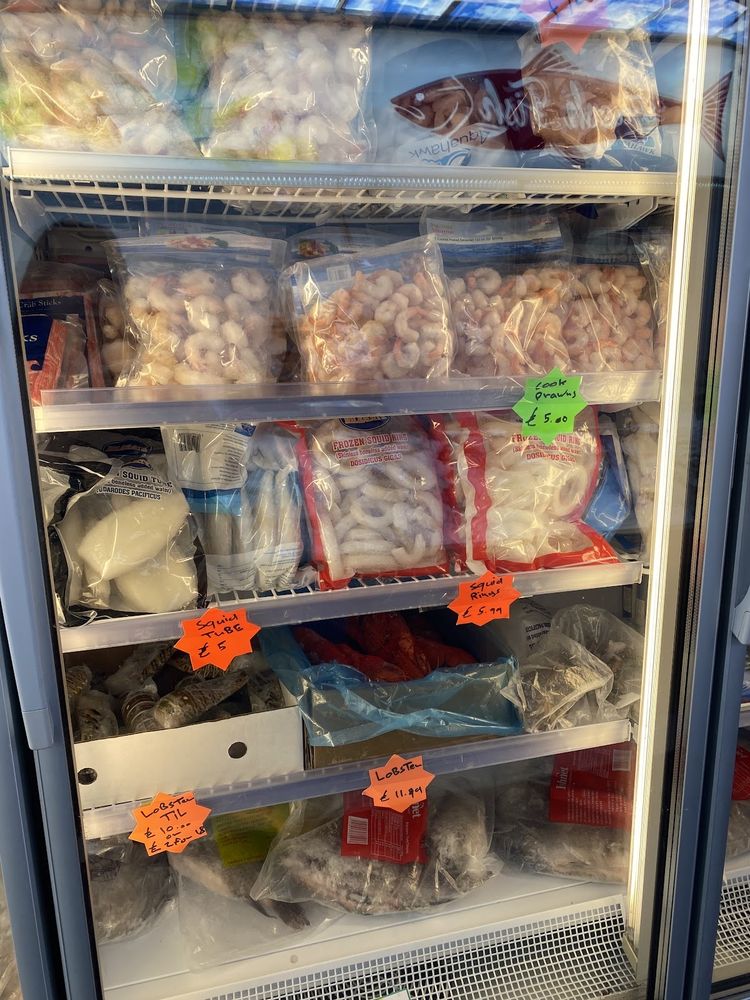 Another angle of the freezer cabinet packed with bags of prawns and frozen fish